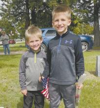 Brothers Bergan (left) and Weston (right) Arens helped place flags at the Ainsworth Cemetery.