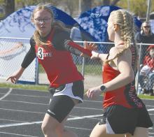 Sophomore Kiley Orton hands off the baton to sophomore Gracyn Painter during the 4x400 meter relay in O’Neill.