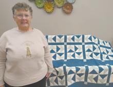 Linda Alberts stands beside a quilt the Sandhills Quilt Guild raffled off during the event.