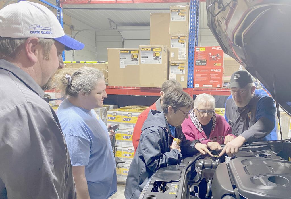 Tony Buckles (left) of 1st Class Auto and Dave Sherman (right) of Buckles Automotive show these ladies what to look for under the hood of their vehicle, locating the antifreeze cap, oil cap and giving them other information which could be beneficial at a later time.