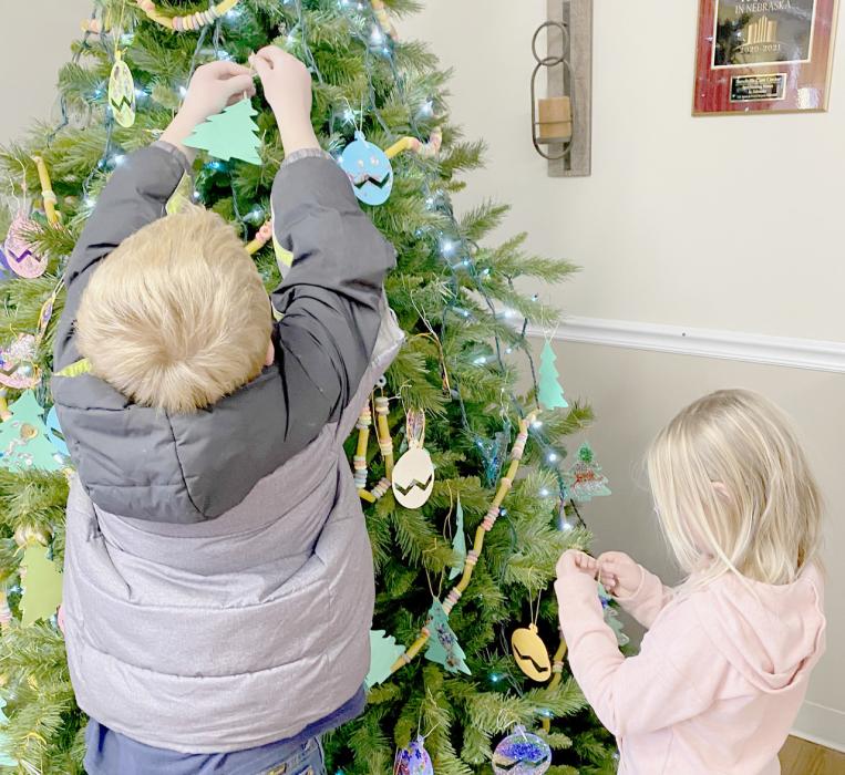 Adding to the finishing touches to the tree with their handmade school ornaments are Suttyn Zeigler and Gracyn Peterson.