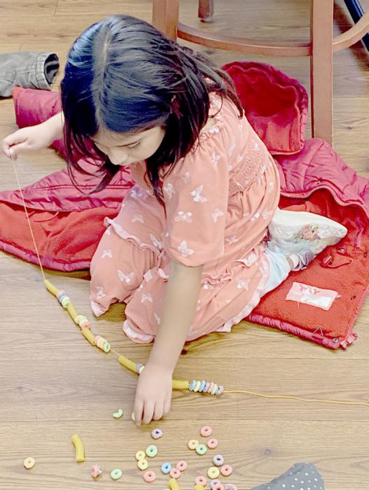 Brenda Carranza picks out the pieces she wants to add next, extending the length of her strand for the garland.