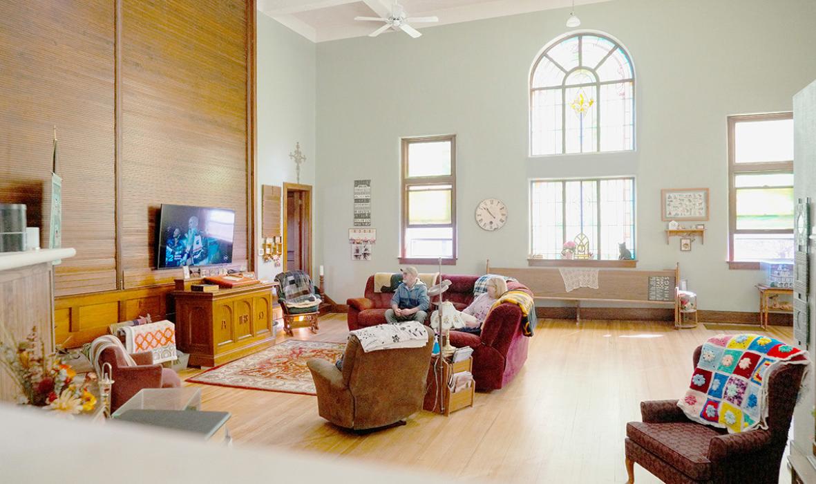 Kathy and Tim Johnson watch TV in their living room in Benedict, Neb., on Sunday, February 18, 2024. The Johnsons purchased an old church that closed in 2020 and turned it into their home. Photo by Naomi Delkamiller/Flatwater Free Press