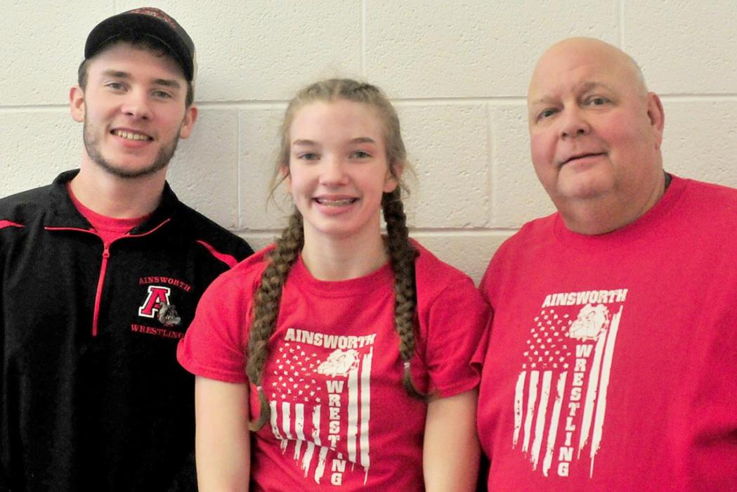 AHS freshman Jolyn Pozehl (center) pinned her way to first place at girls wrestling districts on February 4th and 5th. She will be the first girl wrestler to represent the Bulldogs at the State Wrestling Tournament in Omaha on February 17th - 19th. She is pictured with assistant coach Oren Pozehl (left) and head coach Todd Pollock (right).