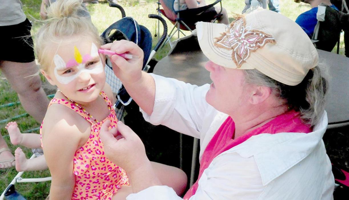 Margaret Walton enjoyed spending time in the shade while doing face paintings. Chazlee Dailey decided on one of the popular designs of the day - a unicorn.