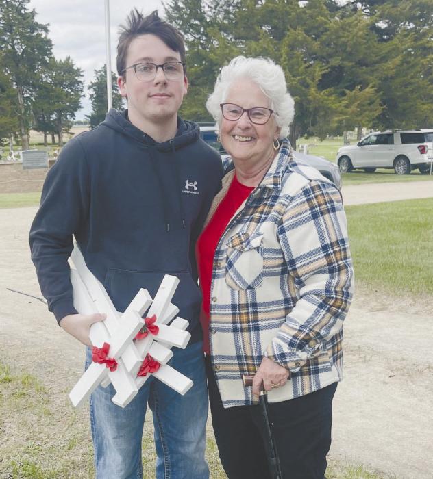 Ryan Salzman and Shari Luther prepared for the Memorial Day Service by placing crosses with poppies on them in the Ainsworth Cemetery.