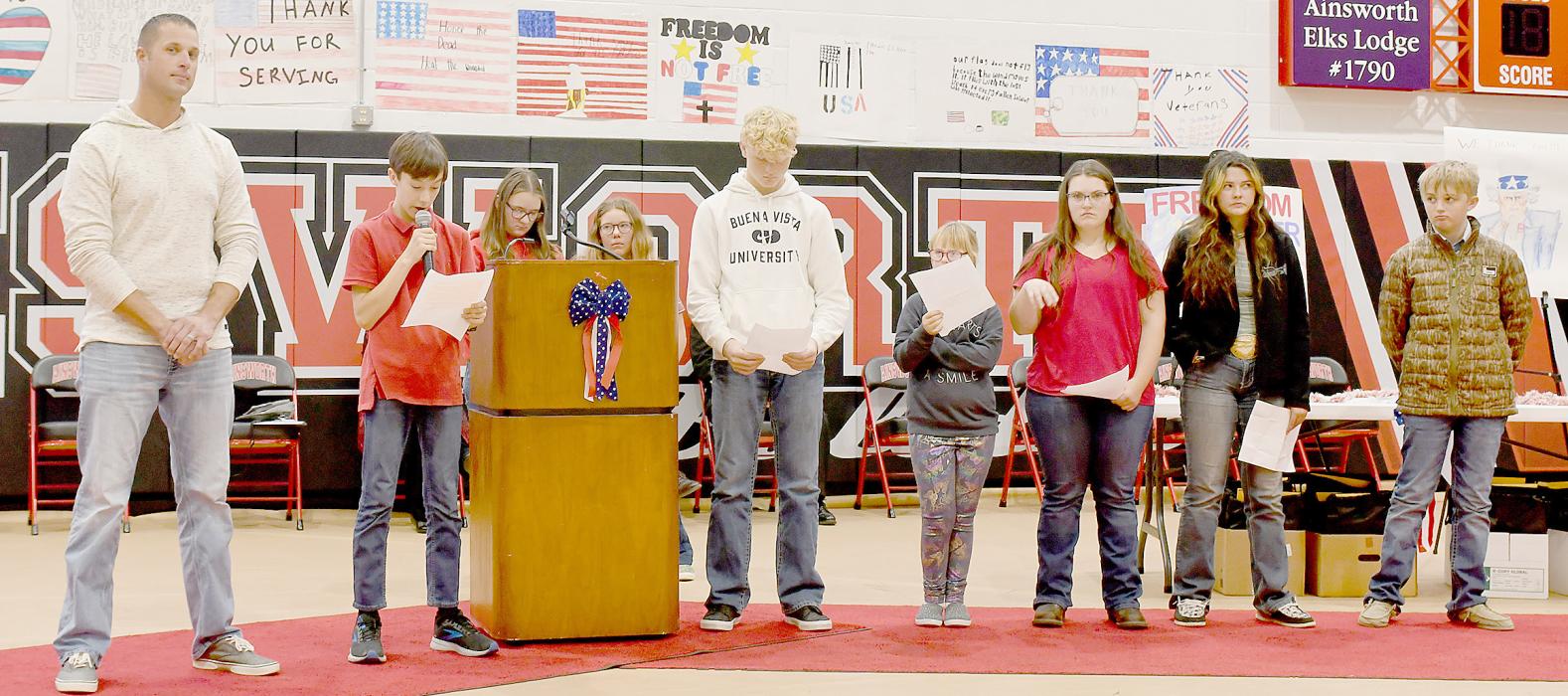 Recognizing the 8th grade classes Adopted Veteran Chris Lammers (left) are classmates (left to right) Ryan Kerrigan, Bristol Goodwin, Lily Beel, Easton McMillan, Haley Happold, Abigail Petty, Kennedei Turpin and Teigen Marbry.