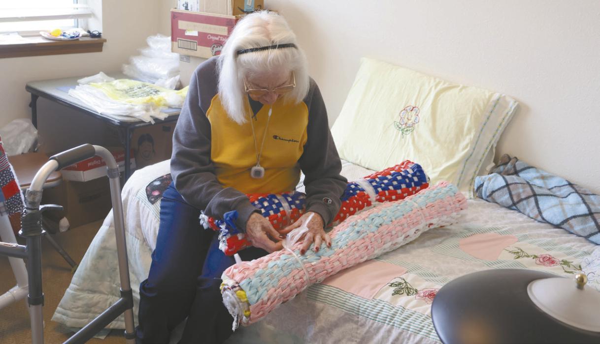 Lila Heerten rolls the mats she recently finished. The three stripes of color on the top of the mat are the identifying marks Lila includes on each mat.