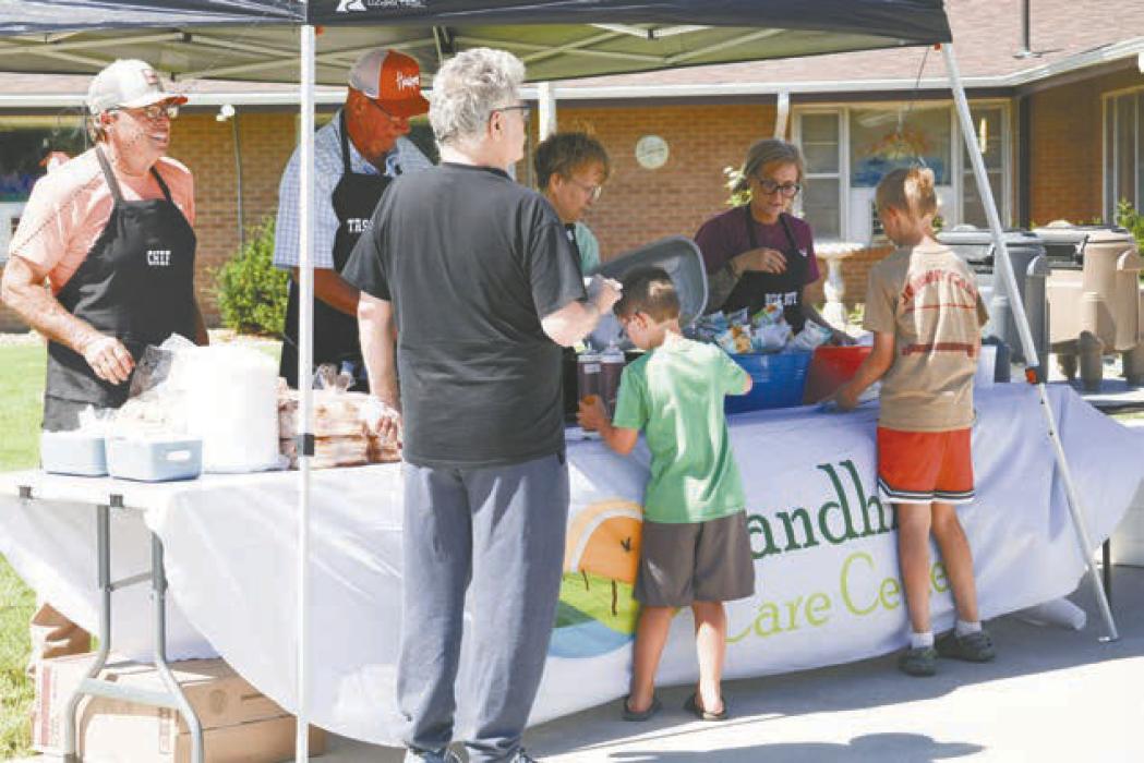 Board members and employees of the Sandhills Care Center served the community during a celebration barbecue for the Care Center reaching full capacity and receiving a national award.