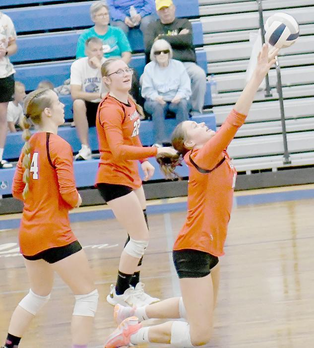 Teammates Gracyn Painter (22) and Cheyan Temple (14) watch as Karli Kral (11) goes to her knees to save the ball from hitting the floor and send it back to the Lady Eagles.