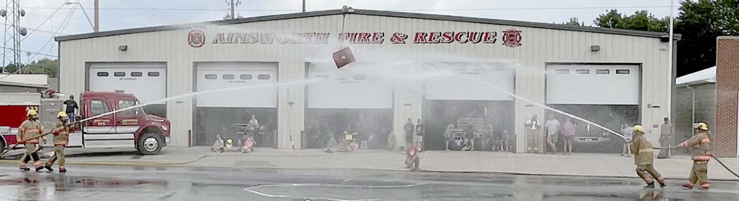 Ainsworth Volunteer Firemen hosted the water fights in front of the fire hall on 3rd Street. It was a warm day with a gloomy sky overhead. Idea of the water fights is to get the barrel on the cable to the other sides team to be declared the winner.