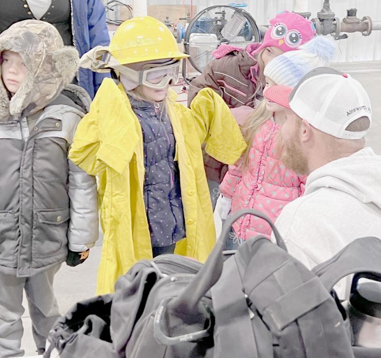 Always a treat, is when the kids get to put on the fire gear to see what it feels like. Drake Fiala helped some youth put on a helmet, goggles and fire coat.
