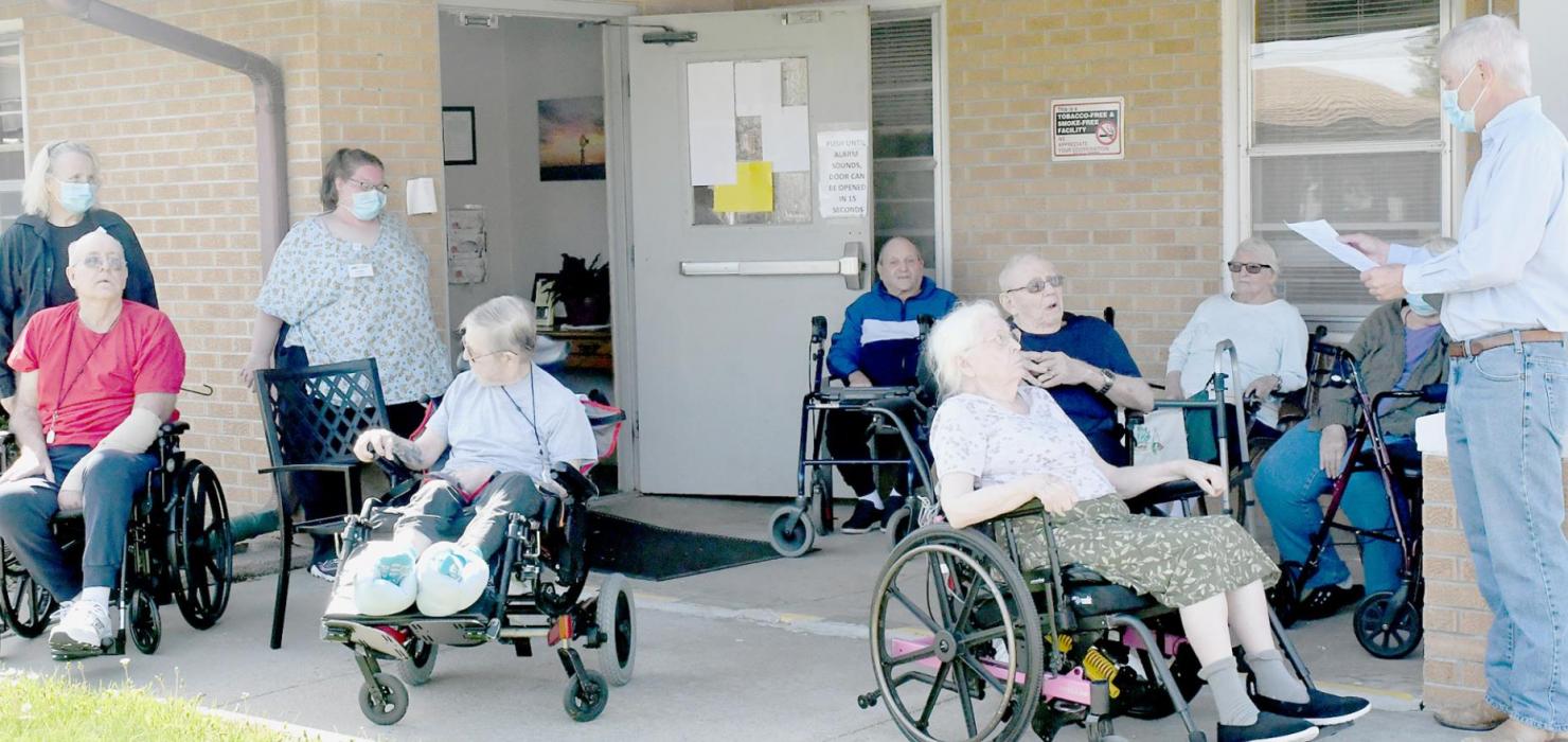 Sandhills Care Center residents and staff gather outside the center on May 9th to hear Mayor Joel Klammer, read (above) and sign (below) a Proclamation that declared May 8 - 14, 2022 as National Skilled Nursing Care Week in Ainsworth.