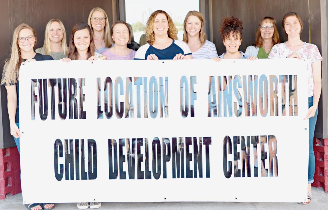 Displaying the sign above are the Board Members of Ainsworth Child Development Center, Inc., (Front Row - Left to Right): Neiley Arens, Devyn France, Karen O’Hare, Ana Garcia and Ashlie Wright; (Back Row - Left to Right): Chelsey Peterson, Rylee Pierce, Nancy Steinhauser, Reagan Fairhead and Marsha Fuchs.