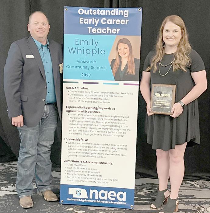 Emily Whipple (right) was awarded the Outstanding Early Career Teacher Award by the Nebraska Agricultural Educators Association (NAEA) at the NAEA Awards Ceremony. Nebraska FFA Alumni Representative Bret Nunnenkamp (left) stands with Whipple and a banner that will travel the state this year and is currently set up on UNLs East Campus.