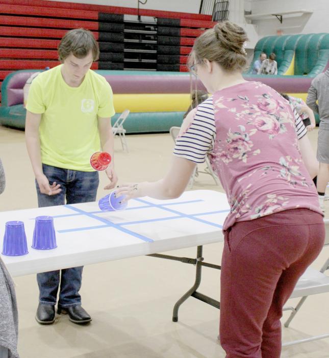 Senior Jaycily Johnson and her date, Brett Alder of Atkinson play the Tic Tac Toe game by flipping a solo cup in one of the square outlined on the table top.