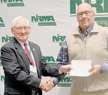 Brown County Commissioner Dennis Bauer receives a dividend check from his fellow County Commissioner Buddy Small, who serves on the NIRMA Board of Directors.