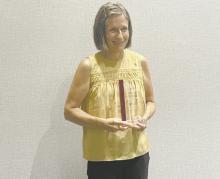Geraldine Erickson stands with her Distinguished Service Award plaque.