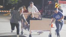The bed race team of Karissa Beck, Jocelyn Good, Karli Kral, and Gracie Kinney push the bed down Third St. as April Good rides atop the bed. The team placed last after some troubles shucking a corn cob during the team’s challenge.