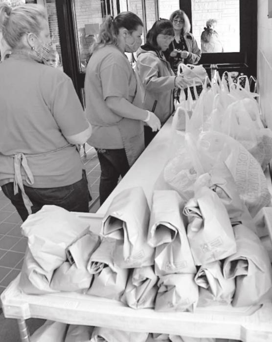 Photo to the left: Staff from Lunchtime Solutions and Ainsworth Community Schools hand out the meal bags to each student.