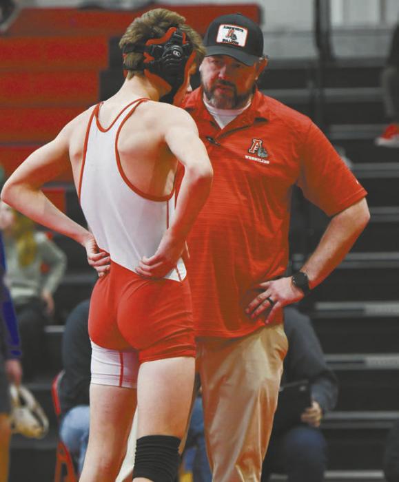 Head coach Jake Graff talks with Holden Beel during his final match of the day. Beel placed first at the Ainsworth Invitational.