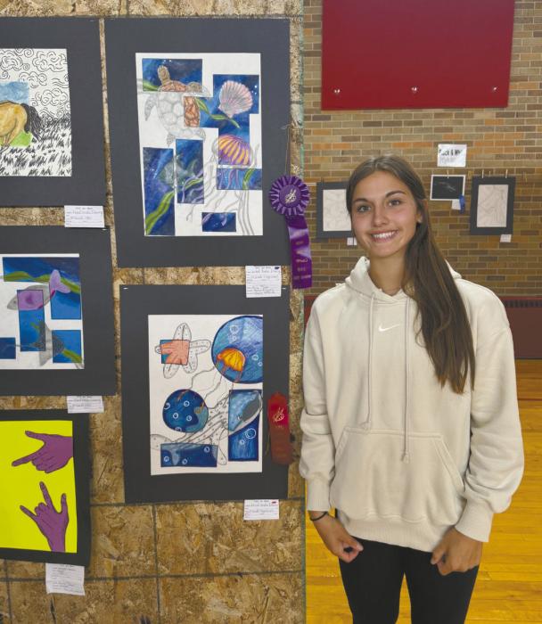 Junior Willa Flynn stands with her entry into the art show that earned her a “Judge’s Choice” purple ribbon.