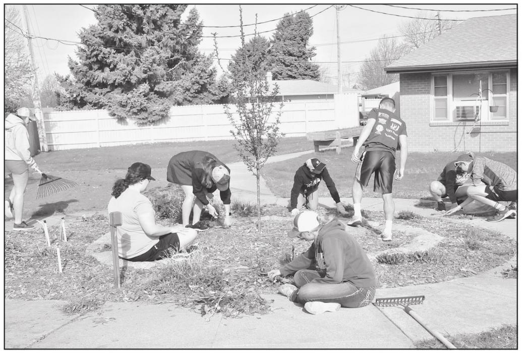 Junior class students clean up the flower beds at the Sandhills Care Center on Friday.