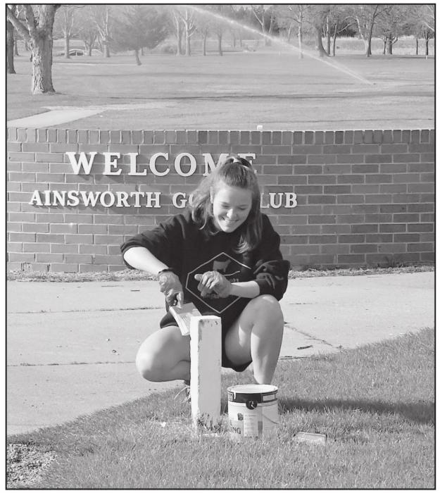 Senior student CeeAnna Beel paints an out-of-bounds marker at Ainsworth Municipal Golf Course.