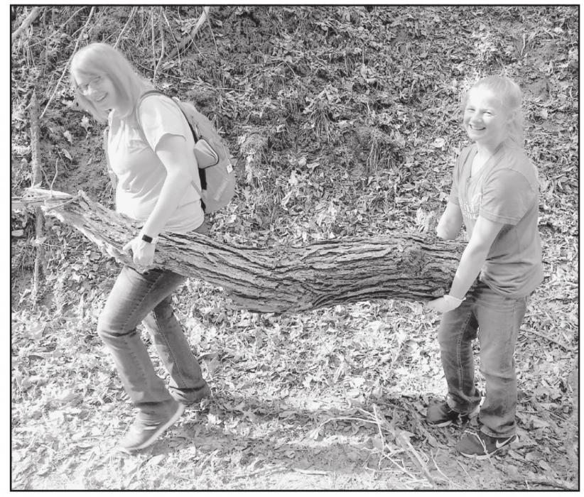 Miss Hancock (left) and sixth grader Addison Held (right) carry a large limb off the trail in Long Pine SRA.