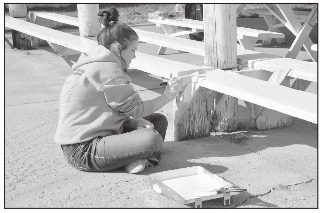 Junior student Wryllie Killion paints benches at the Brown County Fairgrounds in Johnstown.