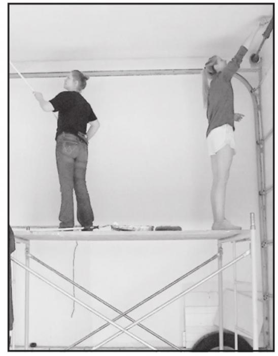 Two students paint the ceiling of the Johnstown Fire Department.