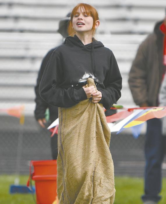 Fifth grader Monroe Buckles cheers on her classmates as she hops in the sack race.