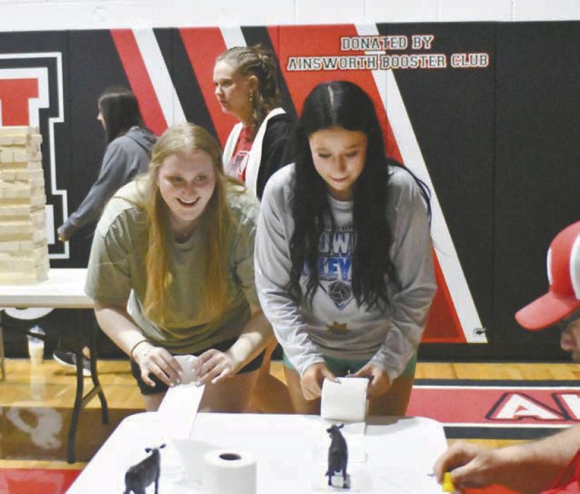 Seniors Addah Booth (left) and Christina Fernau (right) play the toilet paper game run by Clint and Katie Painter.