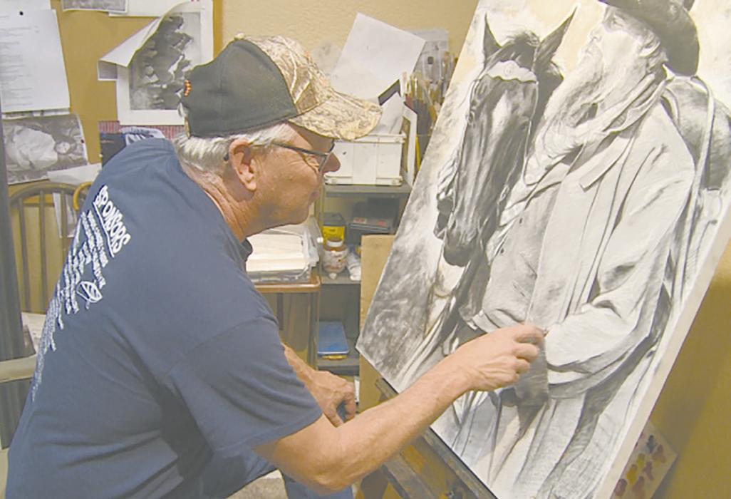 Dorsey works on a piece of artwork with charcoal. Dorsey’s primary focus is western art.