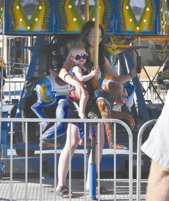 Hope Ripley takes her daughter, Linna, on the carousel on the opening day of the carnival. This year, the carnival returned to Main Street in Ainsworth. In 2024, the carnival was in Long Pine due to road construction..