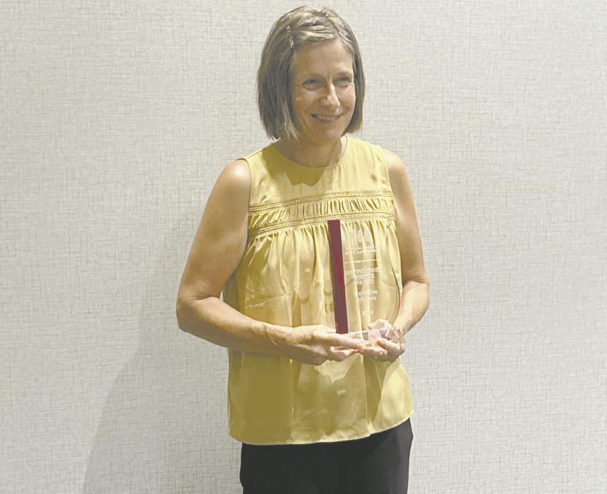 Geraldine Erickson stands with her Distinguished Service Award plaque.