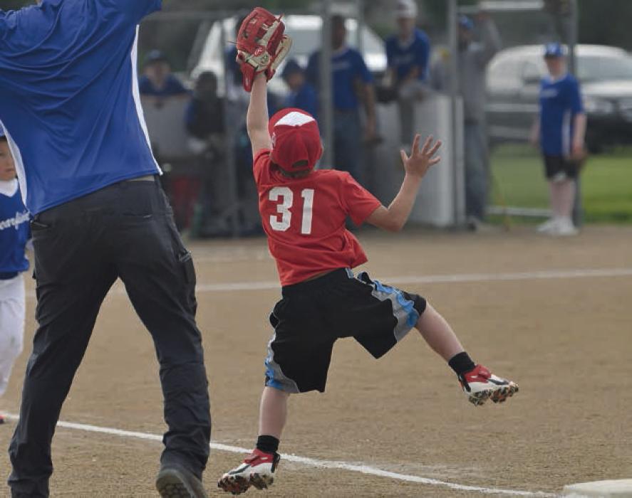 A ball is caught by the first baseman on the Ainsworth’s Rookies baseball team.