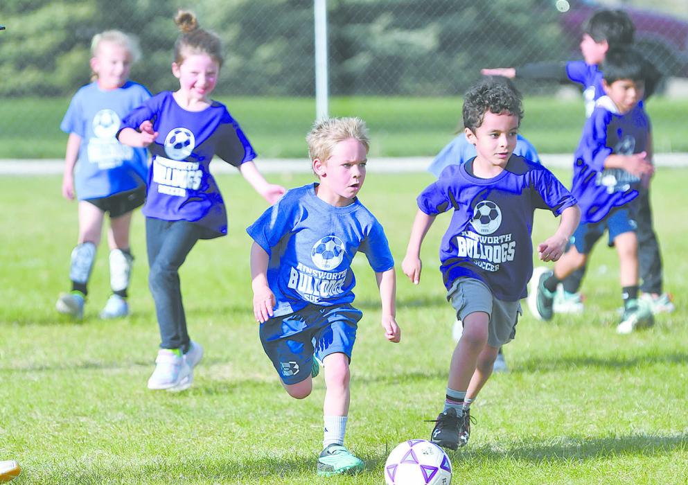 Grady O’Hare (left) kicks the ball down the field as Nathan Martinez (right) guards him during the Pre-K and Kindergarten game.