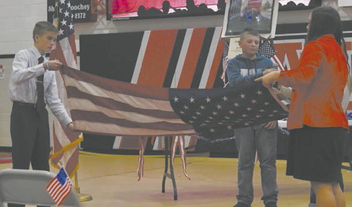 Blake Hansmeyer (left) and Adeline Hladky (right) along with their seventh-grade classmates performed a flag folding during the program.
