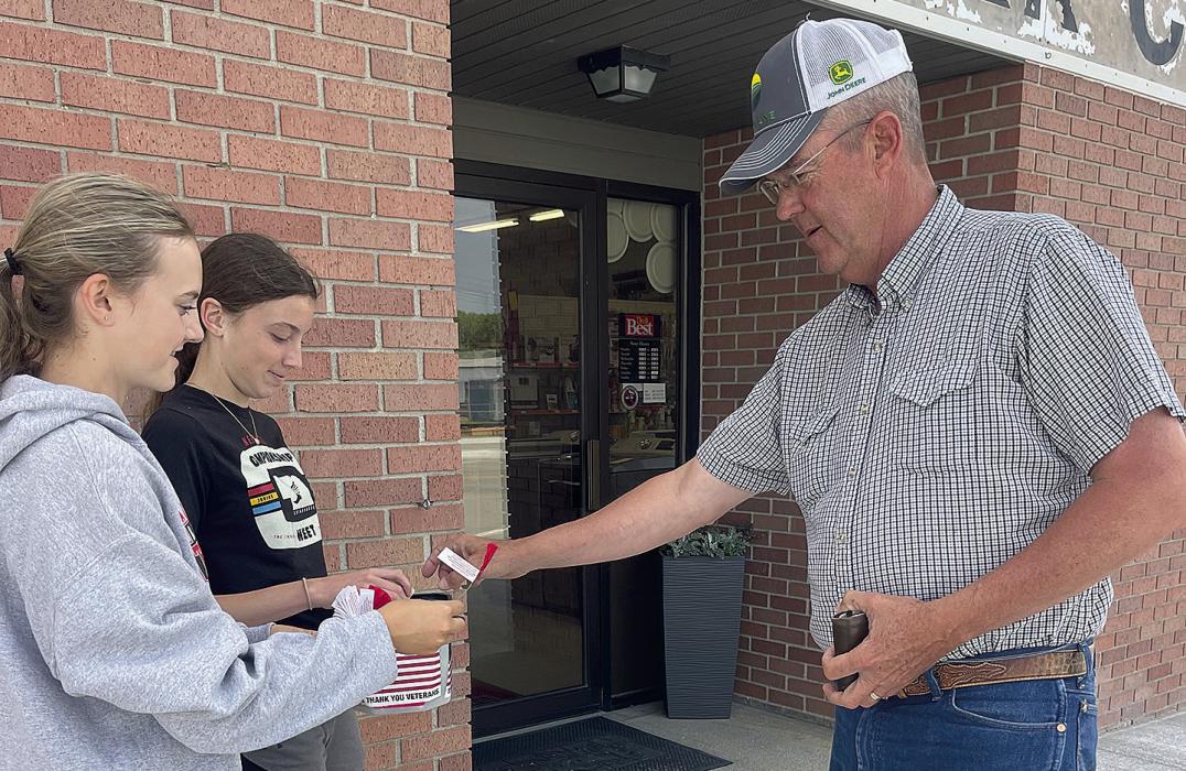 Gracyn Sisson (left) and Reagan Moody (center) sell a poppy to Rex Micheel. In total, the Junior Auxiliary collected $427.17 during their poppy sale.