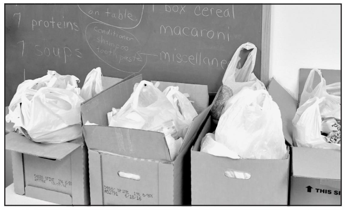 Boxes of food and other items sit waiting for families to pick them up. Volunteers put items in the boxes, including a balanced combination of vegetables, fruits, proteins, starches and other essentials. This year, some pantry items that are in high need are canned fruits, soups and diapers.