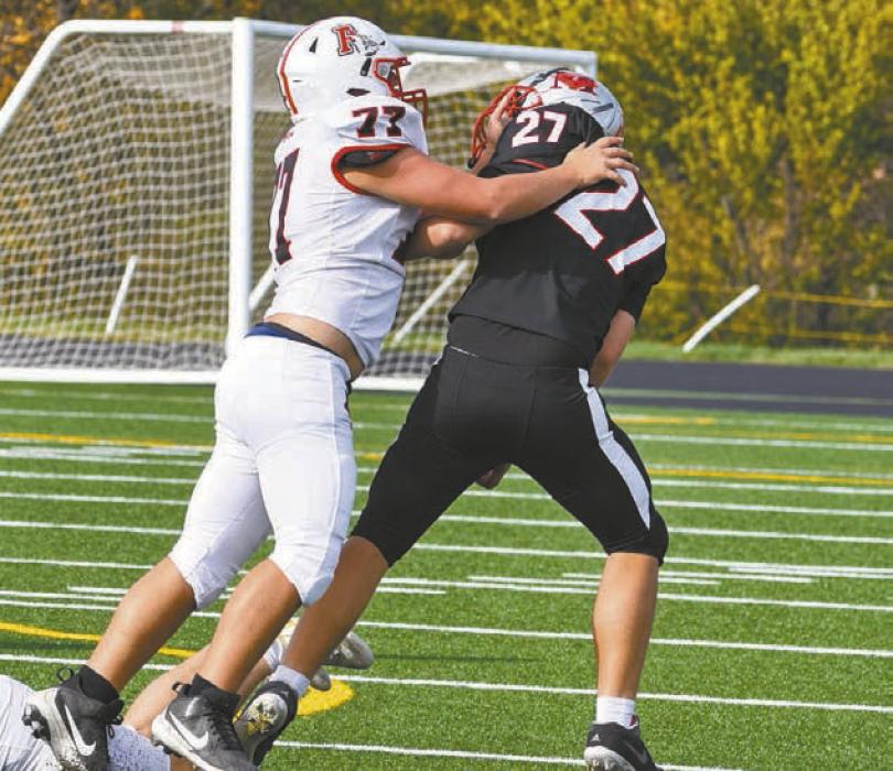 Junior Carson Koch (77) works to tackle Madison's Ernesto Cienfuegos (27).