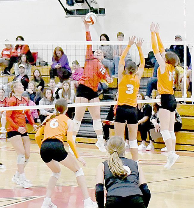 Jocelyn Good (12) reaches high to send the ball back across the net. Teammate Kendyl Delimont (7) is ready to assist her.
