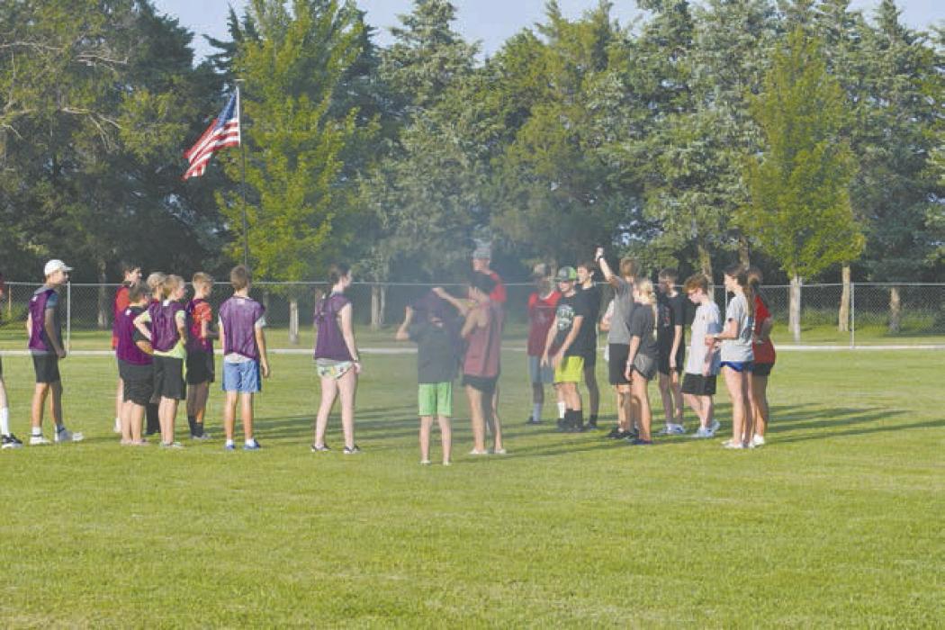 Coach Trey Schlueter explains to the cross country team the rules of ultimate frisbee.