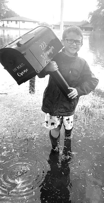 Deakon Crane holds his mailbox, which was damaged during the storm. Some areas of Ainsworth experienced flash flooding during the downpour on Saturday.