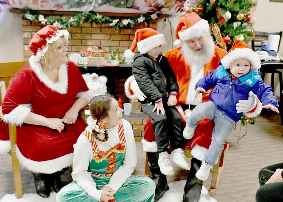 Taking time to sit on Santa’s lap very quickly, was Hooper Mencl (right) and Eli Mencl (left) was his brother. Mrs. Claus and their helper Elf smile as Hooper is ready to go back to mom.