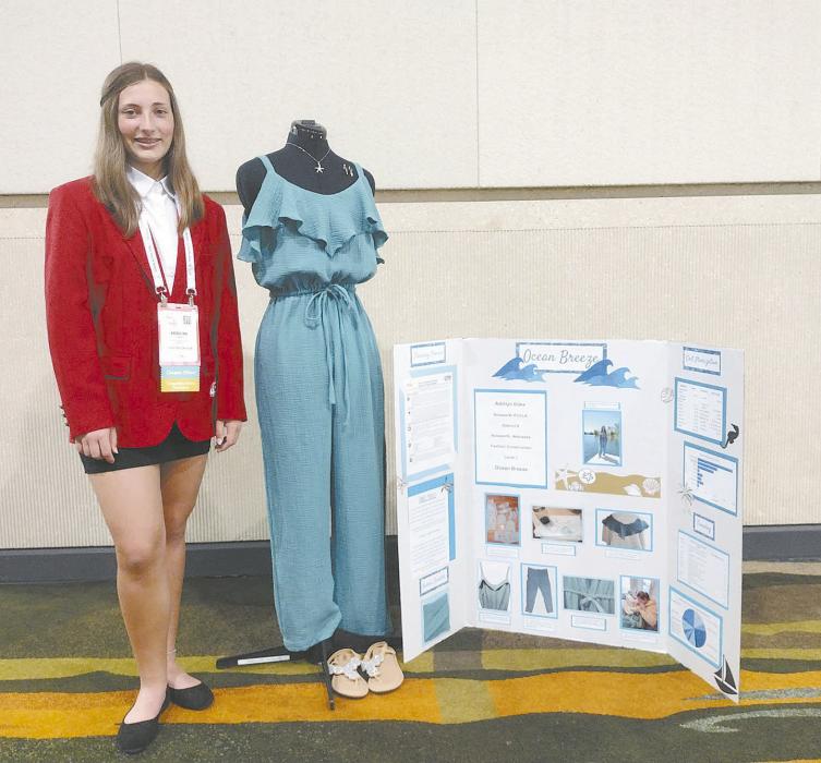 Doke stands with her fashion construction project, a flowy jumpsuit. Doke learned how to sew a waistband for this project.
