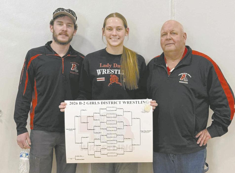 Megan Jones stands with coaches Oren Pozehl (left) and Todd Pollock (right) after she won the district championship in her final district meet. Jones’s season record before state is 35-5. She was Ainsworth’s lone state qualifier for the 2025-2026 season.