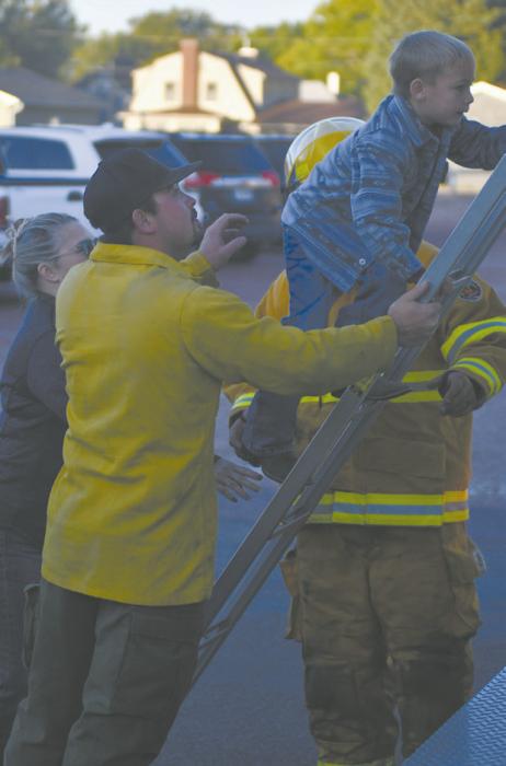 Ainsworth volunteer fireman Caeleb Irwin helps Ainsworth kindergartener Grady O’Hare onto the firetruck.