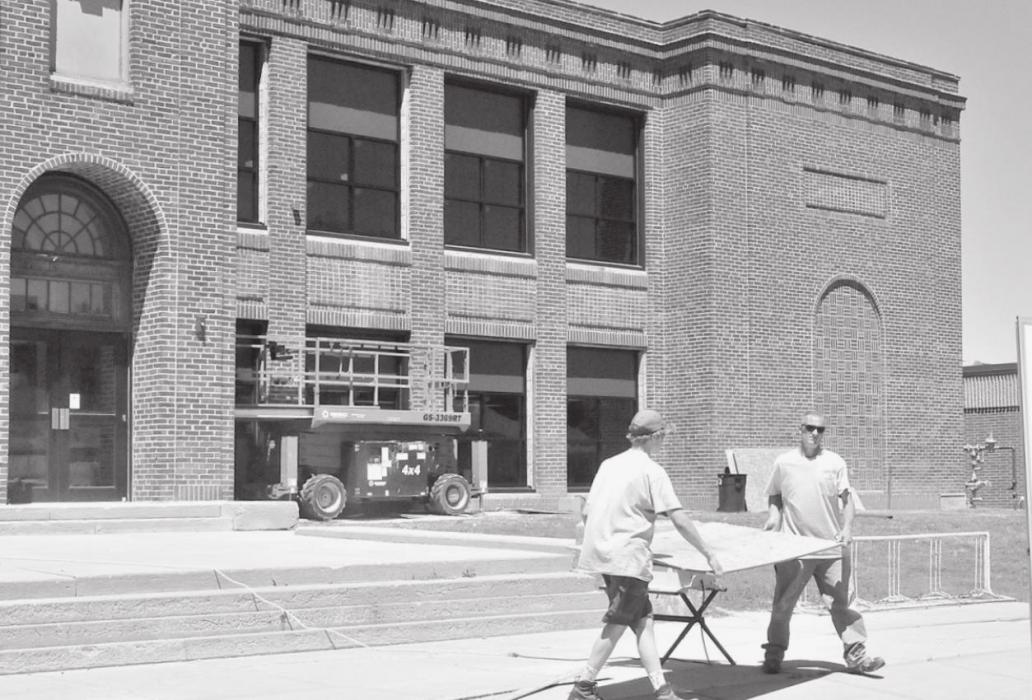 Two workers cut boards to finish installing new school building windows. The windows shown in the photo are already replaced, as were most of the south and west-facing windows on Friday, June 11th.